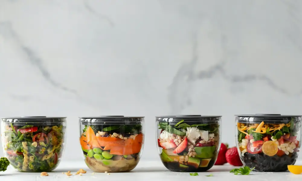 Quatre contenants de batch cooking remplis de repas équilibrés et portionnés d'avance pour la semaine