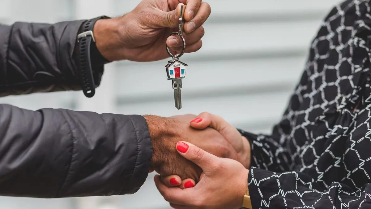 Un agent immobilier fait visiter un appartement à un couple d'acheteurs, contrat de mandat et commission posés sur la table