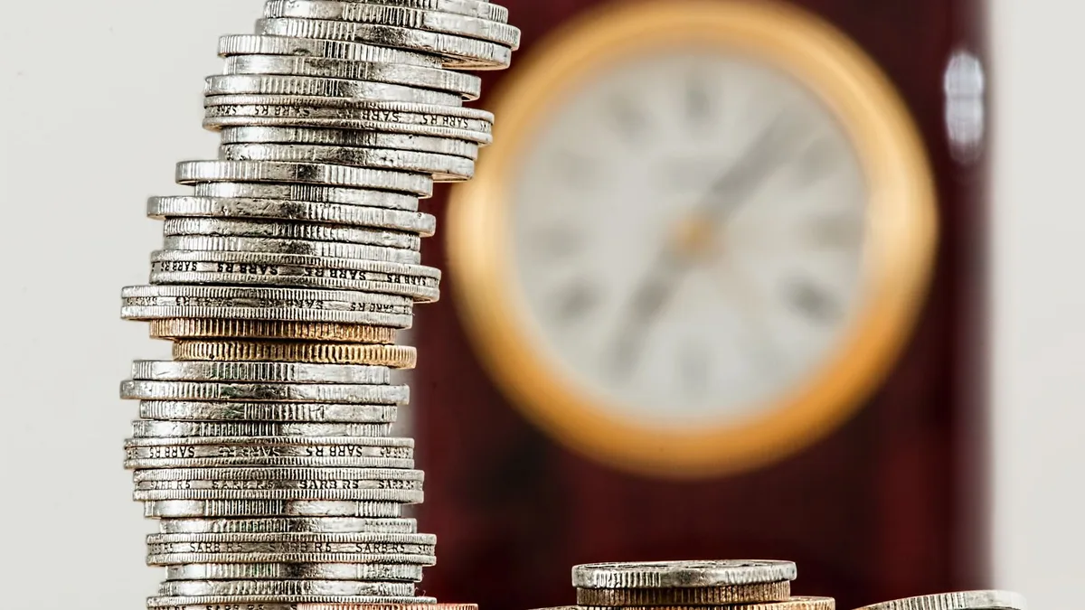 Comment économiser de l'argent rapidement : pile de pièces de monnaie qui grimpe devant une horloge, l'épargne qui se construit dans le temps