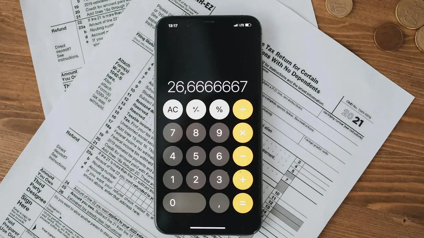 Calculatrice posée sur des formulaires d'impôt avec des pièces en euros, illustration des leviers pour payer moins d'impôts