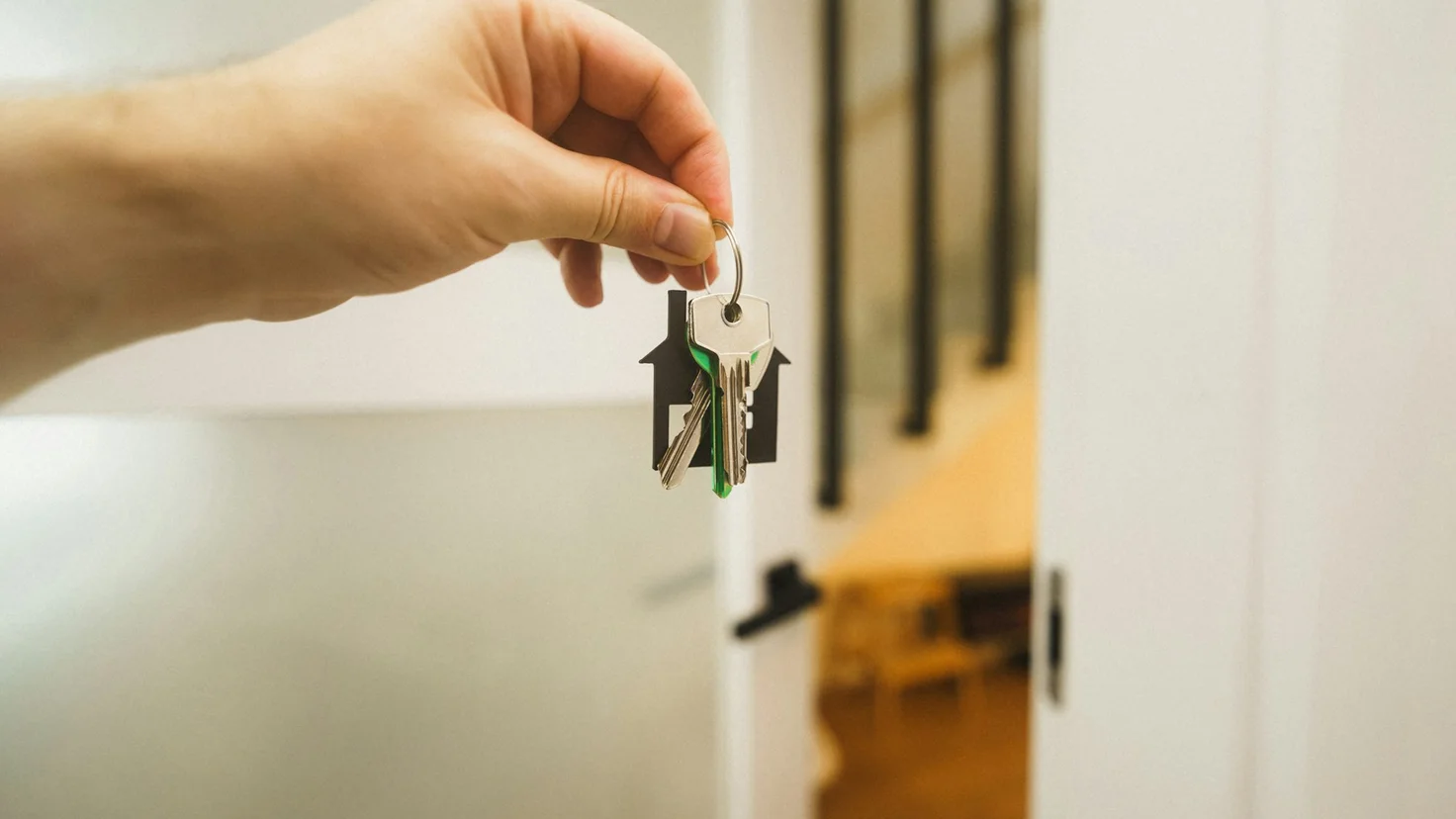 Une main tend un trousseau de clés avec un porte-clés en forme de maison, image d'une donation de son vivant pour transmettre un bien immobilier