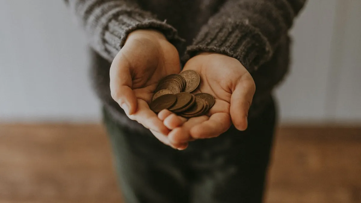 Des mains comptent des pièces avec soin, image de la frontière entre être frugal et radin par choix