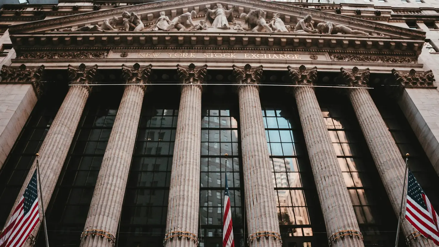 Façade du New York Stock Exchange à Wall Street, drapeaux américains, illustration pour investir aux États-Unis depuis la France en 2026 sans tomber dans les pièges fiscaux
