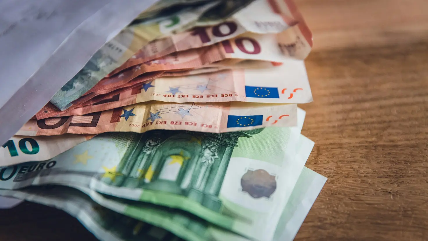 Billets en euros disposés sur une table en bois, illustration du comparatif Livret A contre assurance vie en 2026
