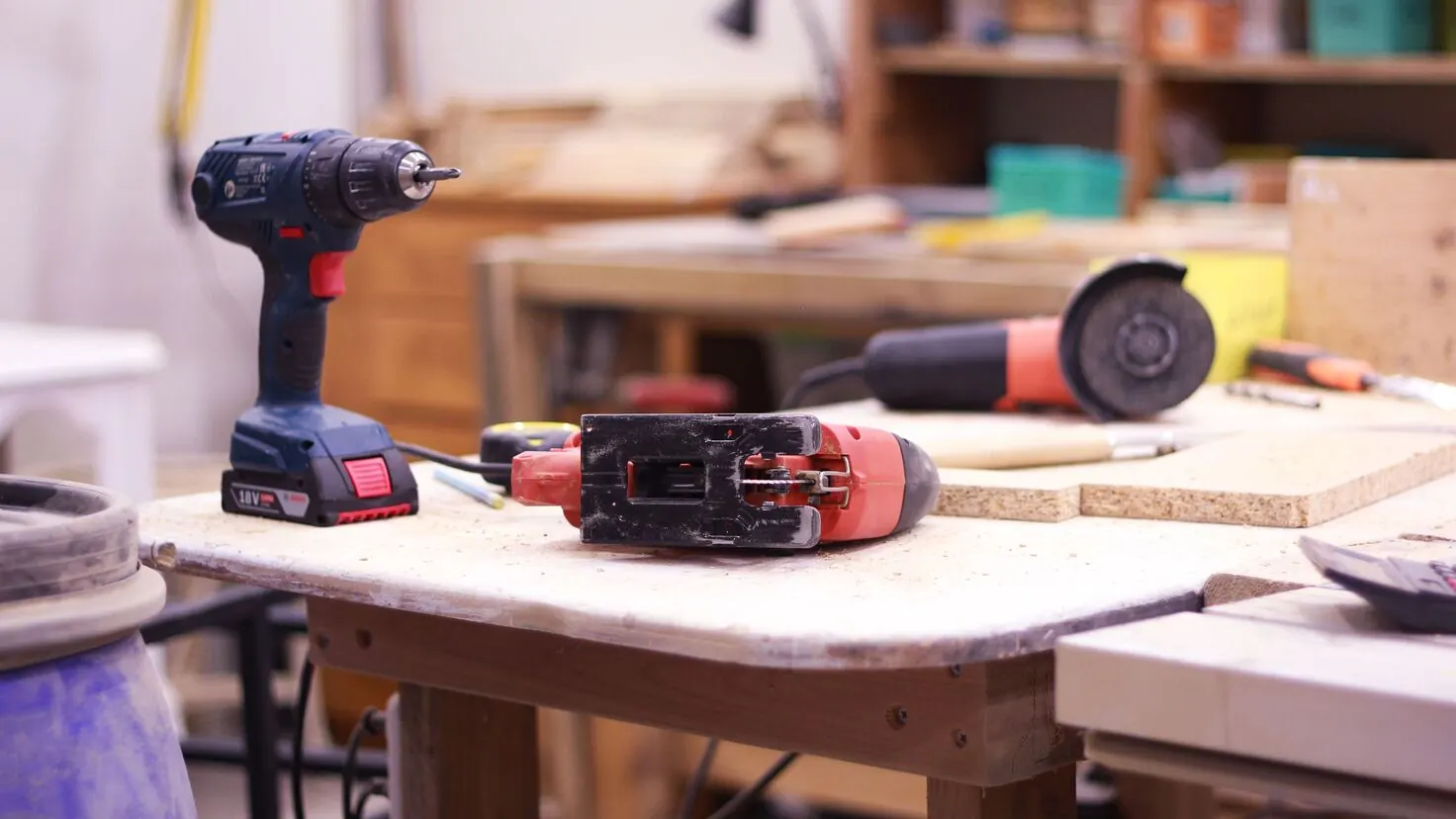 Perceuse, ponceuse et meuleuse posées sur un établi, du matériel de bricolage à louer entre particuliers