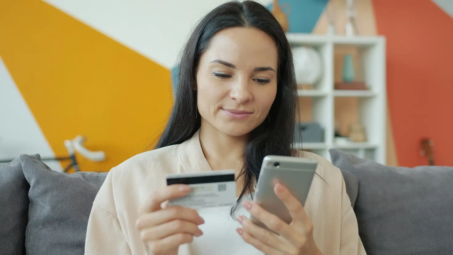 Femme effectuant un paiement en ligne sur son smartphone avec une carte bancaire, illustrant les applications de cashback pour économiser sur ses achats