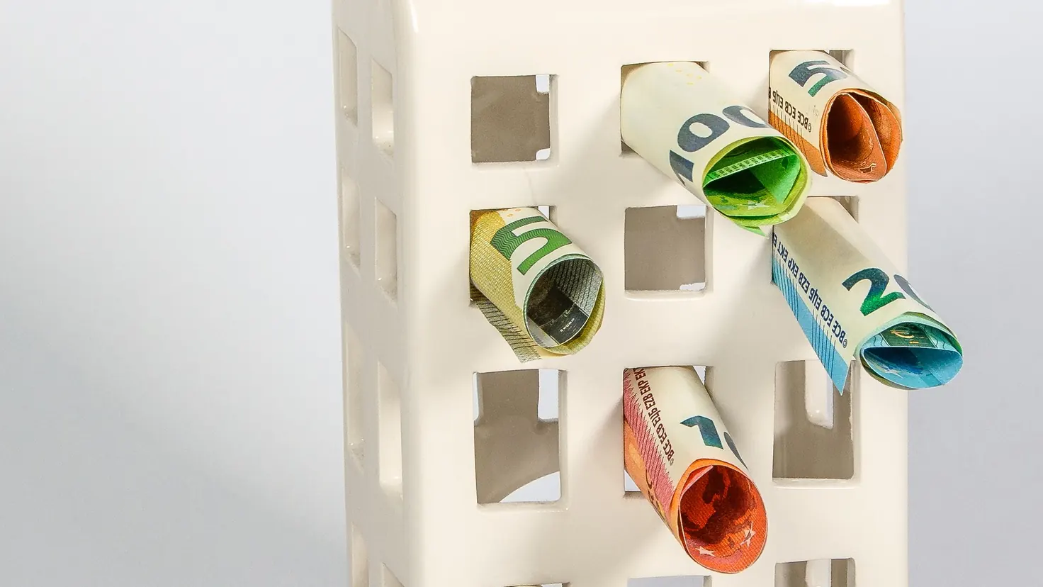 Tirelire en céramique garnie de billets d'euros roulés, illustration de l'épargne salariale et du plan d'épargne entreprise