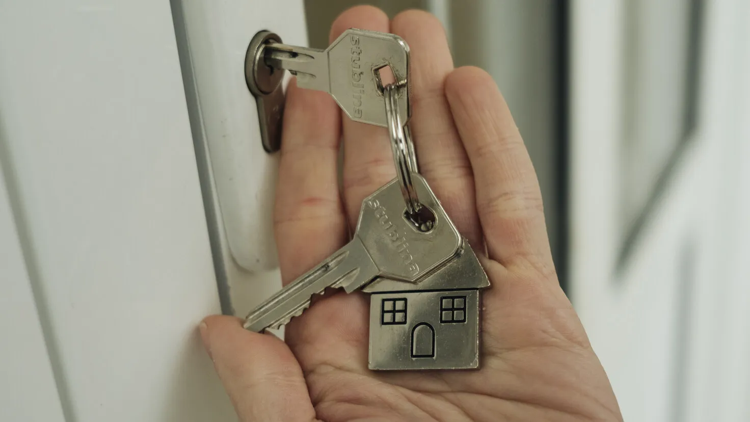 Main glissant une clé dans la serrure d'une porte, illustration d'un projet immobilier préparé avec un plan épargne logement