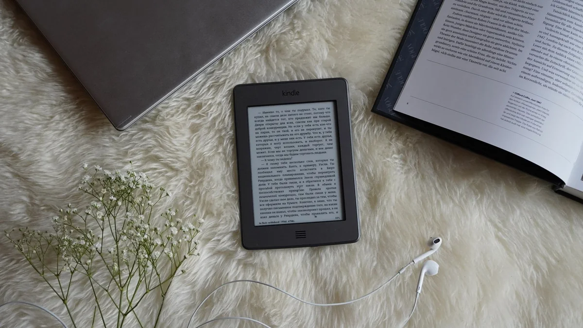 Vendre des livres sur Amazon : une liseuse Kindle posée près d'un livre ouvert et d'un ordinateur, les deux formats de l'auto-édition KDP