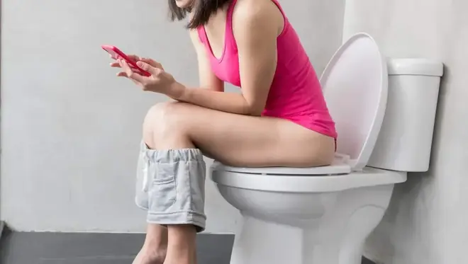 une fille au toilettes avec son smartphone